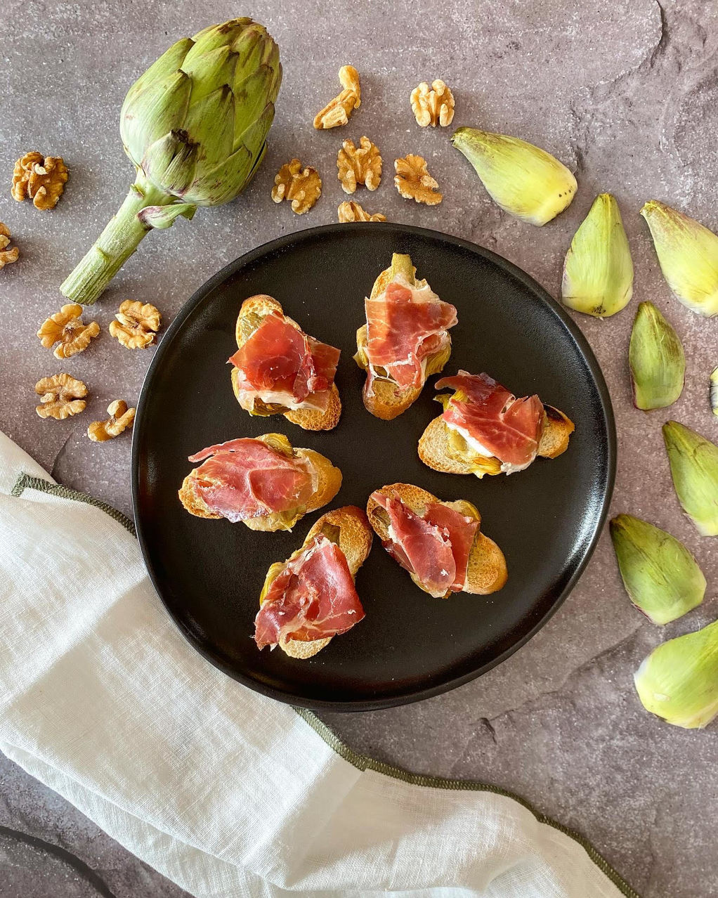 Tostadita de alcachofa confitada con queso de cabra y jamón ibérico